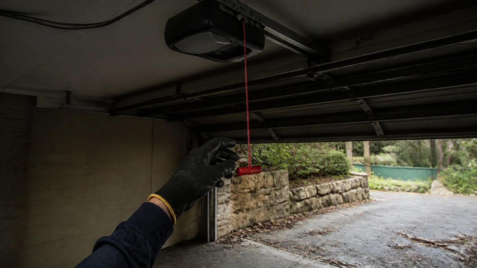 Red manual release cord hanging from a garage door carriage in a Perth Hills garage